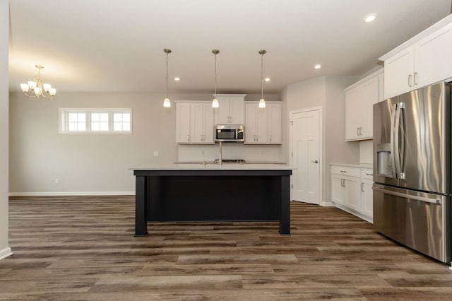 kitchen with pendant lighting, a kitchen island with sink, stainless steel appliances, white cabinets, and dark hardwood / wood-style flooring