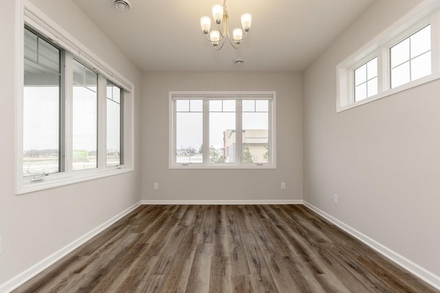 unfurnished room with an inviting chandelier, a healthy amount of sunlight, and dark wood-type flooring