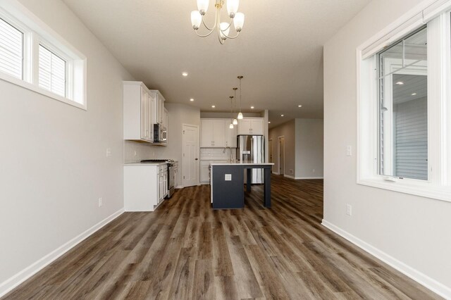 kitchen with a kitchen island, white cabinetry, a kitchen bar, hanging light fixtures, and stainless steel appliances