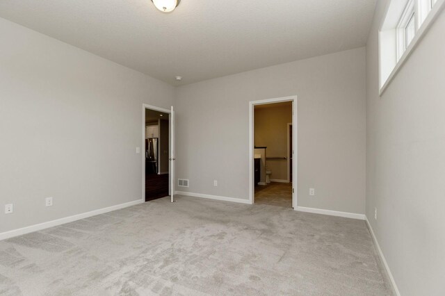 unfurnished bedroom featuring connected bathroom and light carpet