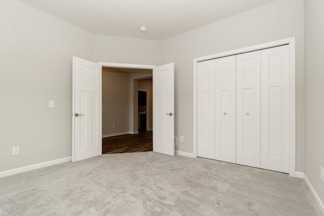 unfurnished bedroom featuring light carpet and a closet