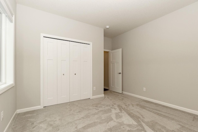 unfurnished bedroom with light colored carpet and a closet