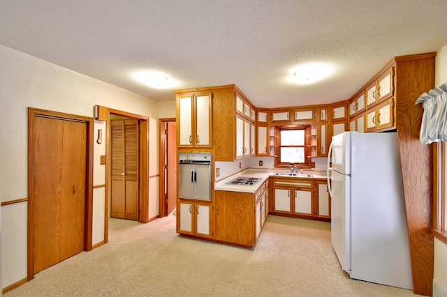 kitchen with a textured ceiling, sink, light colored carpet, and white appliances