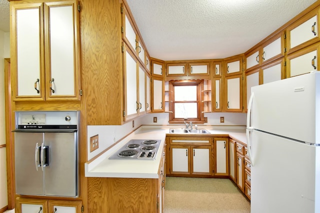 kitchen with light carpet, a textured ceiling, white appliances, and sink