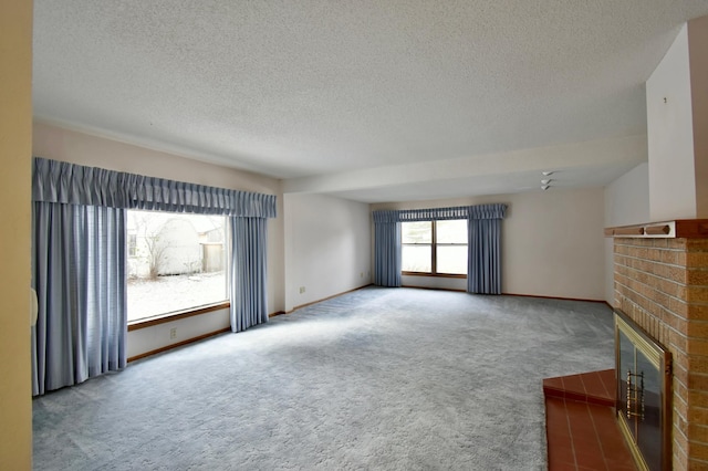 unfurnished living room with carpet floors, a textured ceiling, and a brick fireplace