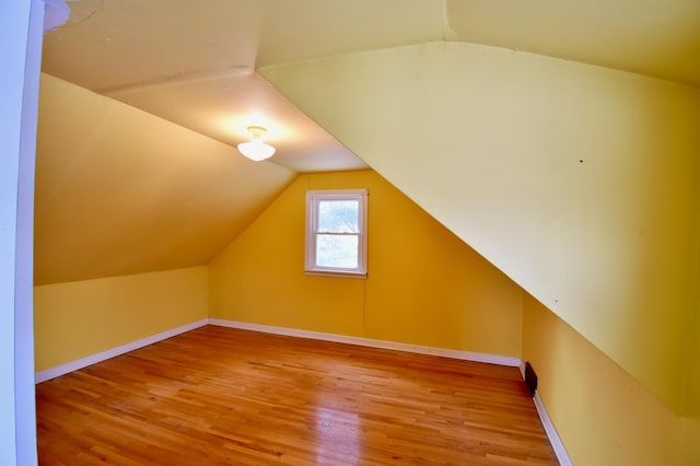 additional living space with hardwood / wood-style flooring and vaulted ceiling