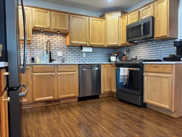 kitchen with appliances with stainless steel finishes, backsplash, dark hardwood / wood-style floors, and sink