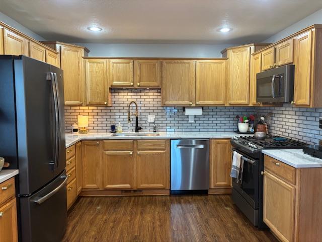 kitchen featuring decorative backsplash, appliances with stainless steel finishes, dark wood-type flooring, and sink