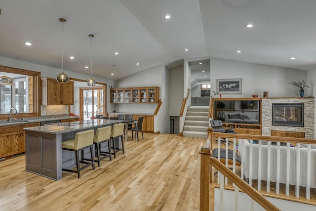5517 Dickson Rd, Minnetonka, MN 55345 - kitchen with lofted ceiling, brown cabinetry, a kitchen island, a kitchen breakfast bar, and light wood-type flooring
