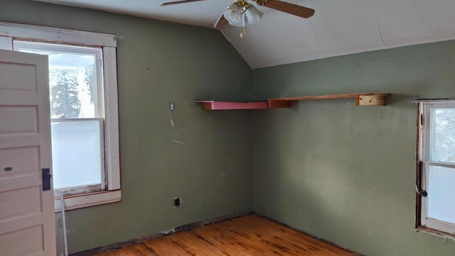 empty room with ceiling fan, vaulted ceiling, and light wood-type flooring