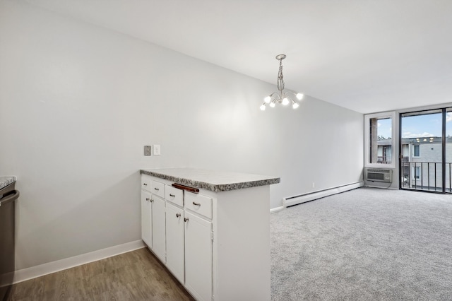 kitchen with kitchen peninsula, a baseboard radiator, a notable chandelier, white cabinetry, and hanging light fixtures