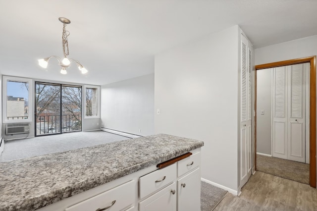 kitchen with a baseboard heating unit, white cabinets, an inviting chandelier, hanging light fixtures, and light hardwood / wood-style flooring