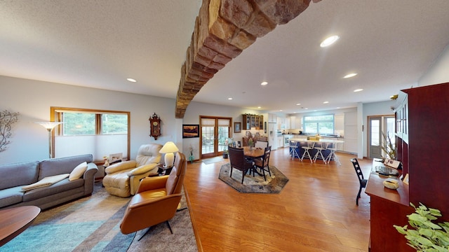 living room with a textured ceiling, plenty of natural light, light hardwood / wood-style floors, and french doors