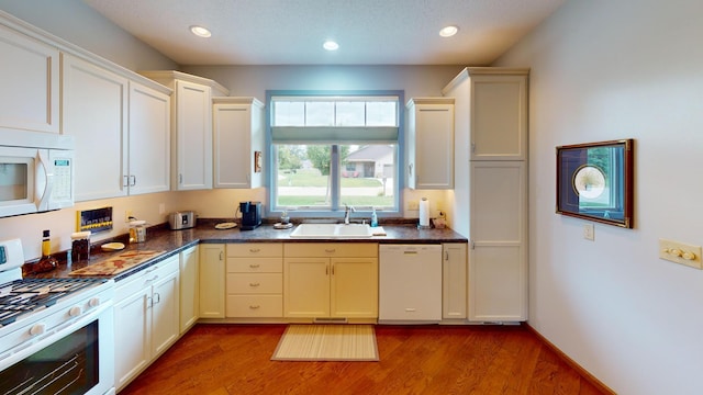 kitchen with hardwood / wood-style floors, white appliances, sink, and a textured ceiling