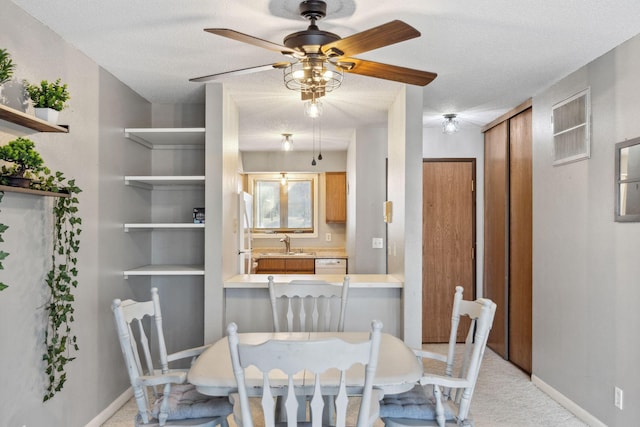 dining space with a ceiling fan, baseboards, a textured ceiling, and light colored carpet