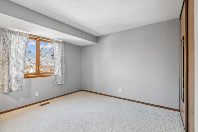 empty room featuring baseboards, a textured ceiling, visible vents, and carpet flooring