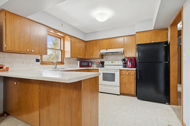 kitchen featuring a peninsula, freestanding refrigerator, brown cabinets, under cabinet range hood, and electric stove