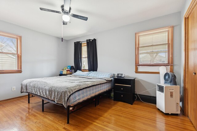 bedroom featuring light wood finished floors, baseboards, a closet, and ceiling fan