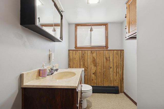 half bath featuring baseboard heating, vanity, and toilet