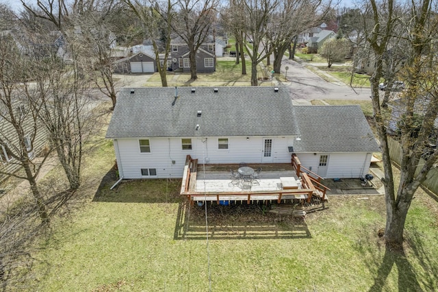back of house featuring a residential view, a lawn, a shingled roof, and a deck