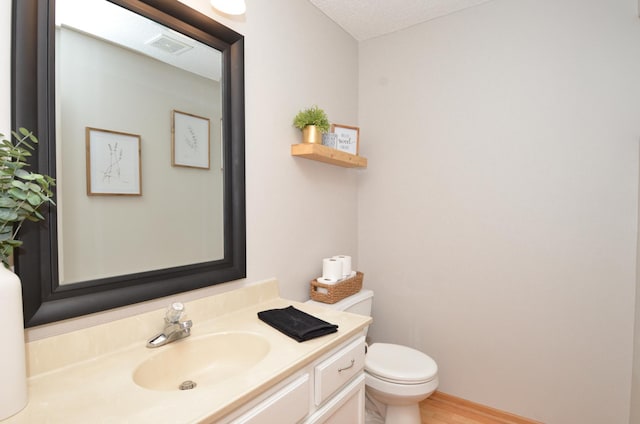 bathroom featuring hardwood / wood-style flooring, vanity, a textured ceiling, and toilet