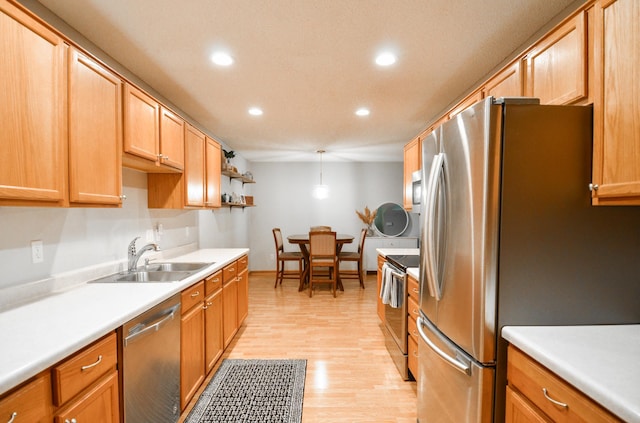 kitchen with decorative light fixtures, light wood-type flooring, stainless steel appliances, and sink