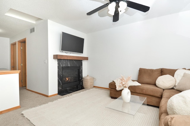 carpeted living room featuring ceiling fan and a textured ceiling