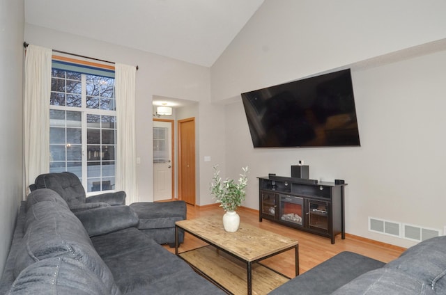 living room with hardwood / wood-style floors and high vaulted ceiling