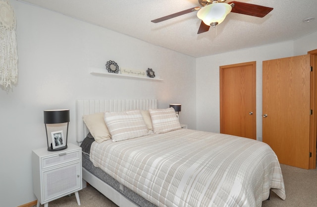 carpeted bedroom featuring a textured ceiling, ceiling fan, and multiple closets