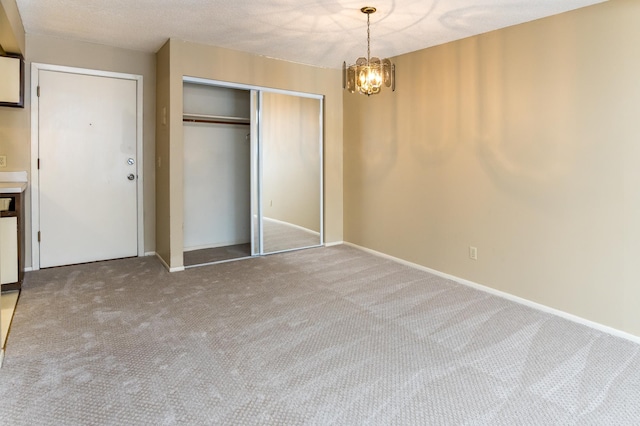 unfurnished bedroom with a closet, carpet floors, and an inviting chandelier