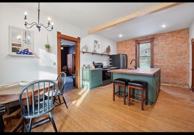 kitchen with green cabinets, brick wall, light hardwood / wood-style floors, electric stove, and a center island with sink