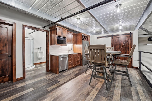 kitchen with a barn door, sink, dark wood-type flooring, and appliances with stainless steel finishes