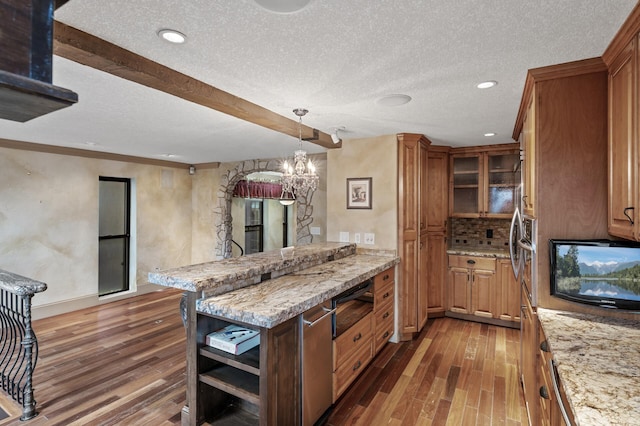 kitchen featuring hanging light fixtures, light stone countertops, a textured ceiling, tasteful backsplash, and dark hardwood / wood-style flooring