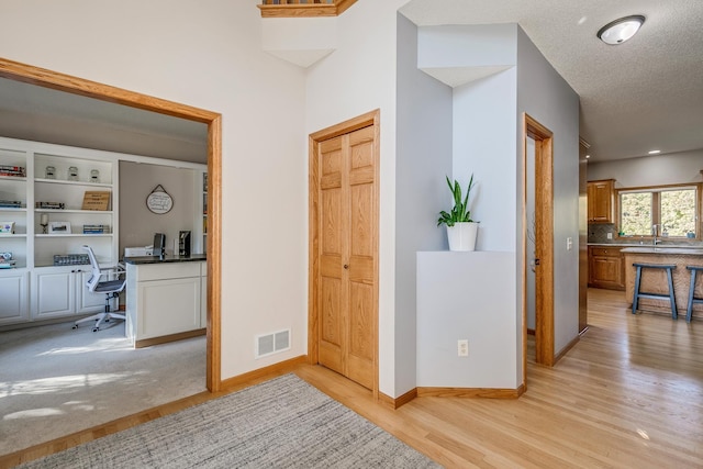 hallway featuring light hardwood / wood-style flooring and a textured ceiling