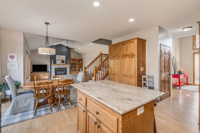 kitchen featuring a kitchen island, hanging light fixtures, vaulted ceiling, and light wood-type flooring