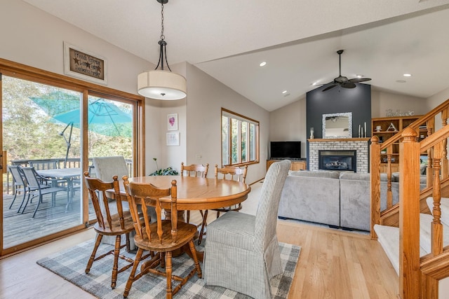 dining area with a fireplace, ceiling fan, light hardwood / wood-style flooring, and lofted ceiling