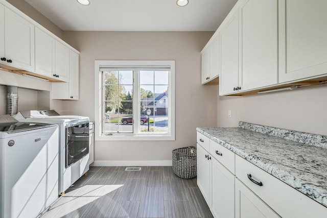 clothes washing area with cabinets and independent washer and dryer