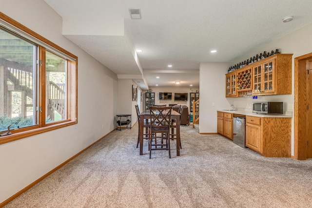 dining area with light colored carpet, a textured ceiling, and bar area