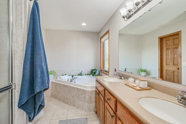 bathroom featuring tile patterned flooring, vanity, a textured ceiling, and tiled tub