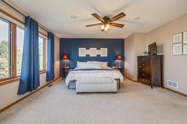 bedroom featuring a textured ceiling, light colored carpet, and ceiling fan