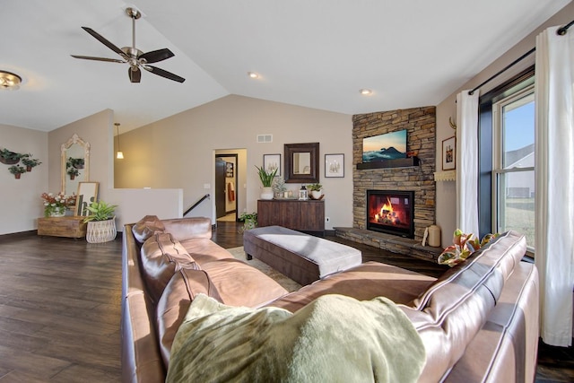 living room with a stone fireplace, a healthy amount of sunlight, dark wood-type flooring, and vaulted ceiling