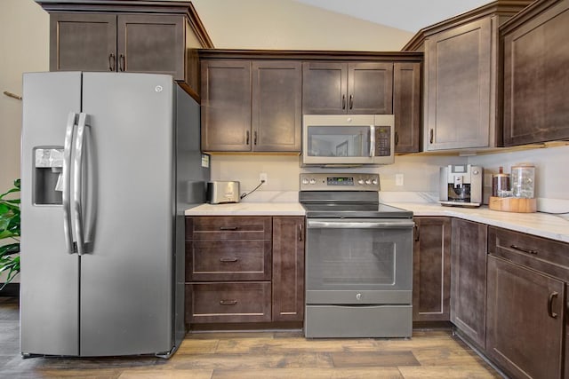 kitchen with light hardwood / wood-style floors, dark brown cabinetry, stainless steel appliances, and vaulted ceiling