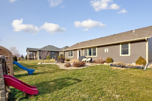 back of house with a yard and a playground