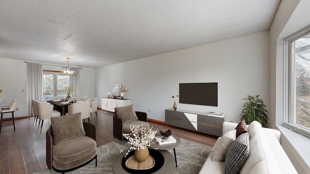 living room with dark wood-type flooring, a wealth of natural light, and a chandelier