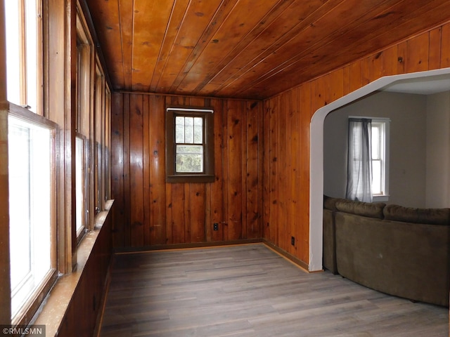 unfurnished room with hardwood / wood-style floors, a wealth of natural light, and wooden walls