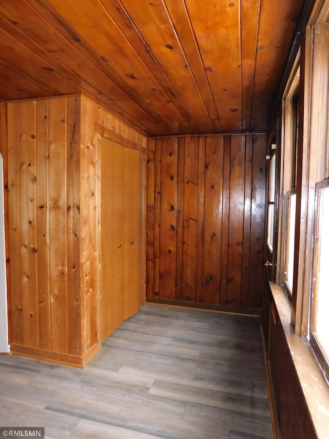 interior space with wood walls, wood-type flooring, and wooden ceiling