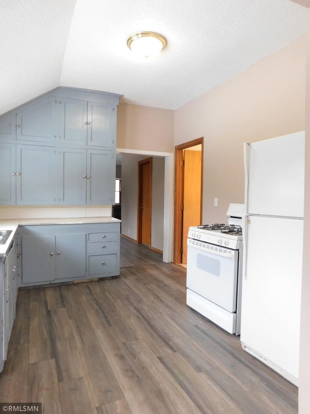 kitchen with a textured ceiling, lofted ceiling, white appliances, and dark wood-type flooring