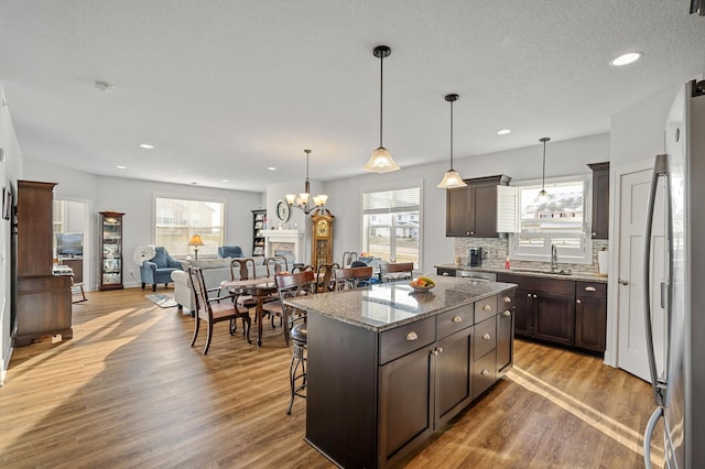 kitchen featuring hardwood / wood-style flooring, dark brown cabinets, a center island, and a kitchen bar