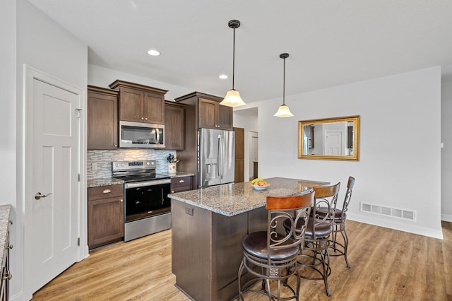 kitchen featuring light stone countertops, light hardwood / wood-style flooring, stainless steel appliances, and dark brown cabinets