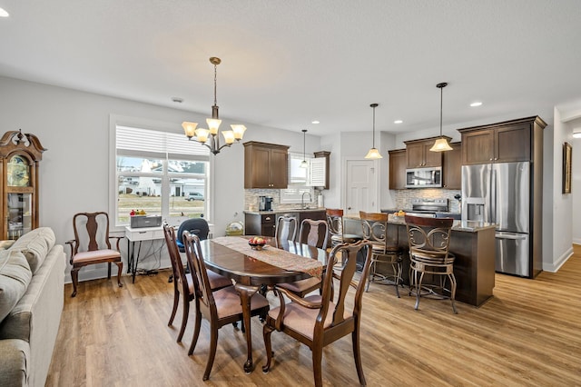 dining space with light hardwood / wood-style floors, an inviting chandelier, and sink